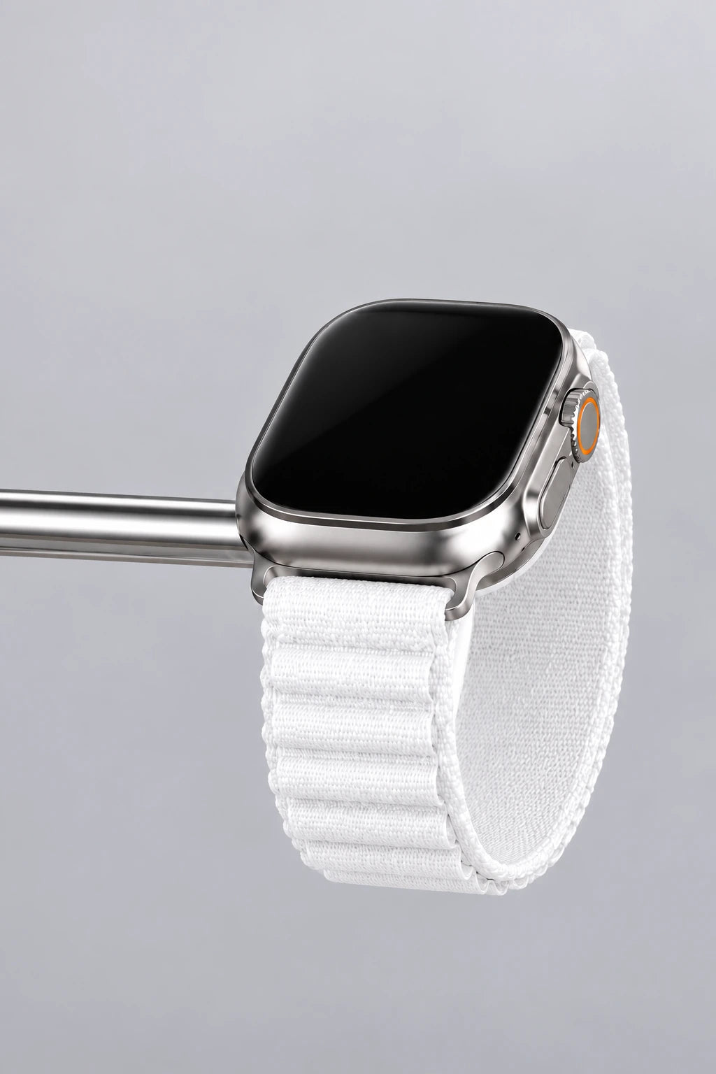 Silver watch with a white band resting on the right-hand charging puck of a chrome dock.